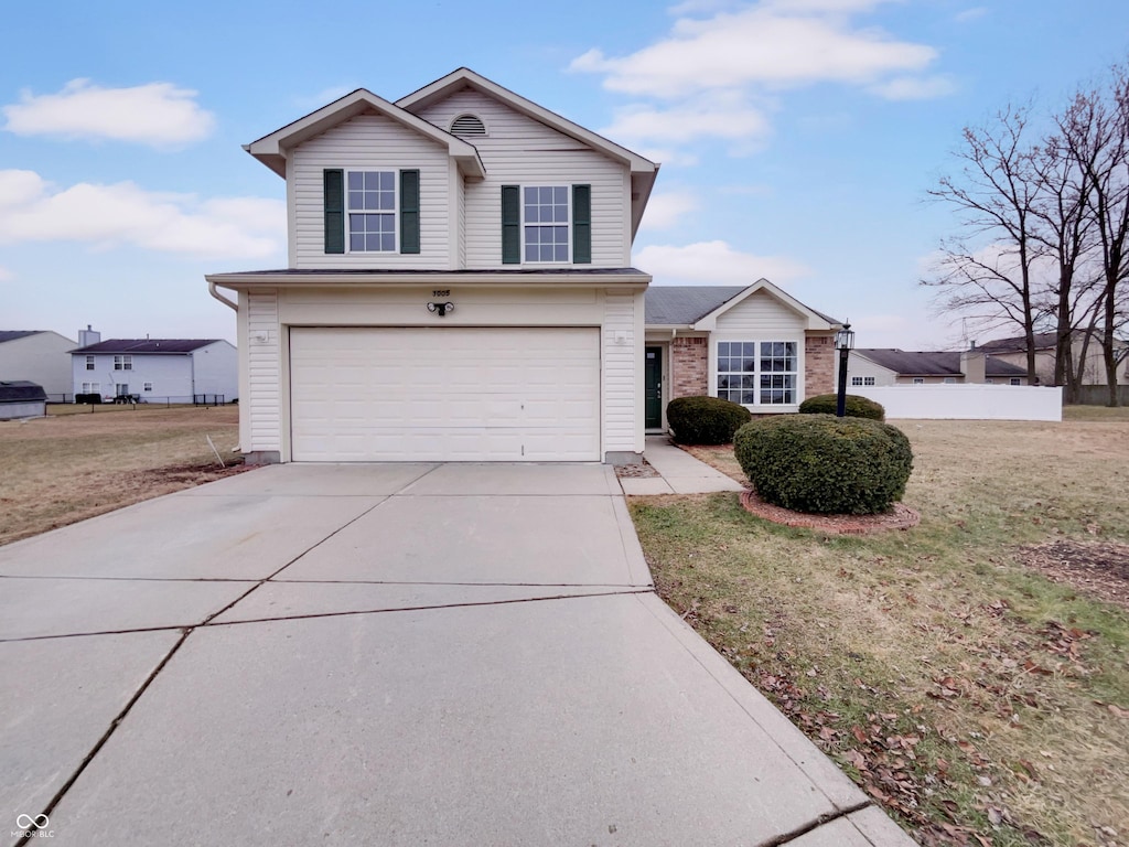 traditional-style house with driveway, an attached garage, and a front lawn