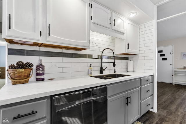 kitchen featuring a sink, black dishwasher, light countertops, dark wood finished floors, and white cabinetry