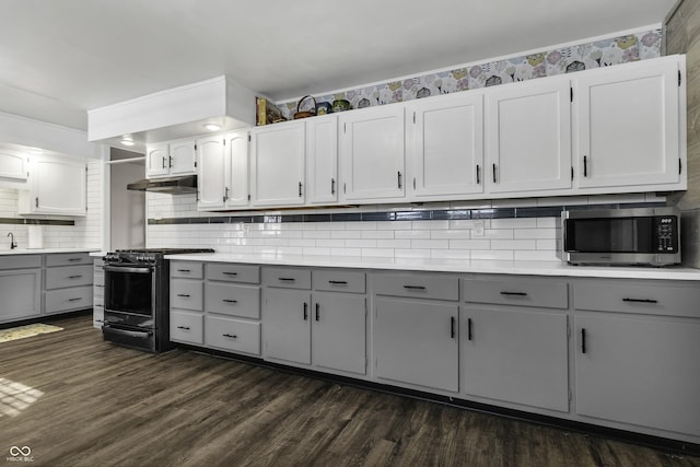 kitchen featuring dark wood-style floors, stainless steel microwave, under cabinet range hood, black stove, and light countertops