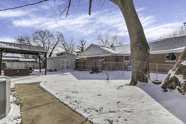 yard covered in snow featuring a shed, fence, and an outbuilding