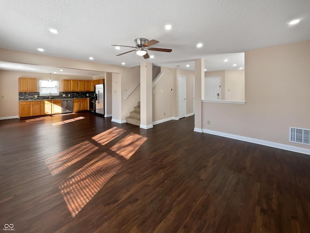 unfurnished living room featuring sink, dark wood-type flooring, a textured ceiling, and ceiling fan