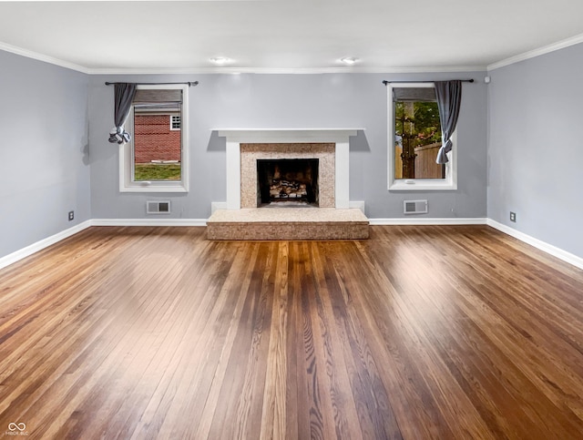 unfurnished living room with crown molding, a wealth of natural light, and hardwood / wood-style floors