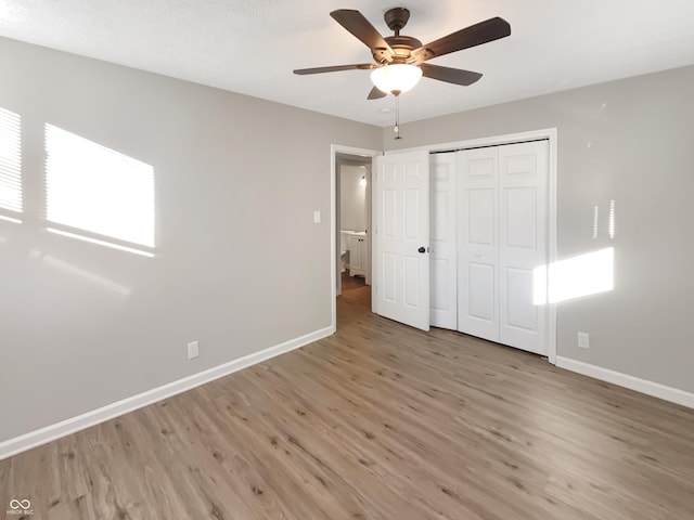 unfurnished bedroom featuring a ceiling fan, a closet, baseboards, and wood finished floors