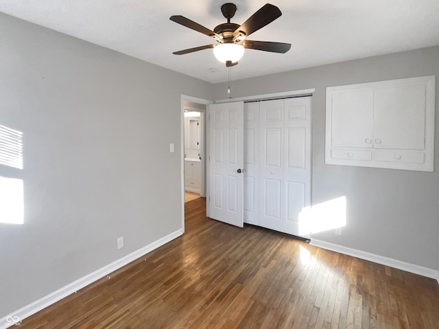 unfurnished bedroom with a closet, dark wood-style flooring, ceiling fan, and baseboards