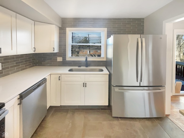 kitchen featuring white cabinets, appliances with stainless steel finishes, a sink, light countertops, and backsplash