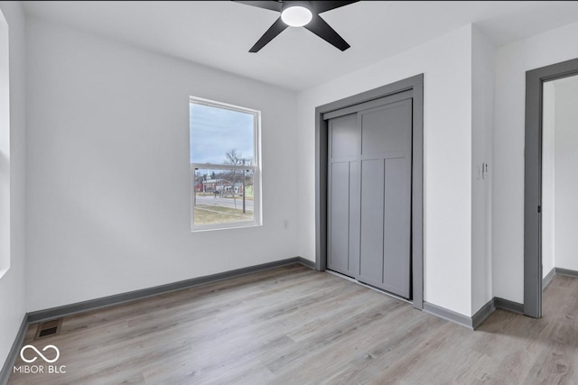 unfurnished bedroom featuring ceiling fan, light hardwood / wood-style floors, and a closet