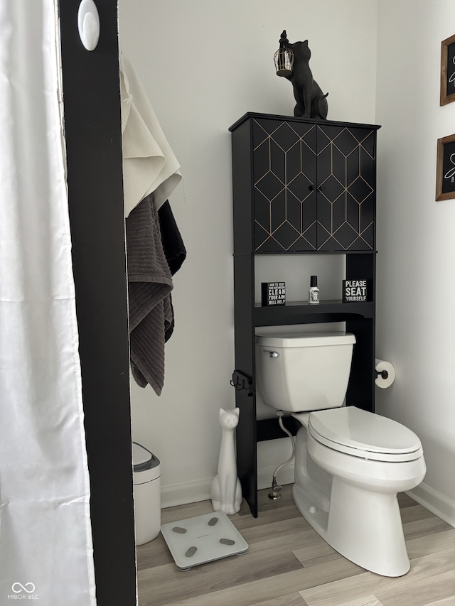 bathroom with baseboards, toilet, and wood finished floors