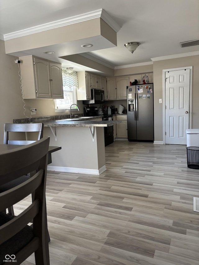 kitchen with a breakfast bar area, a peninsula, visible vents, black appliances, and crown molding