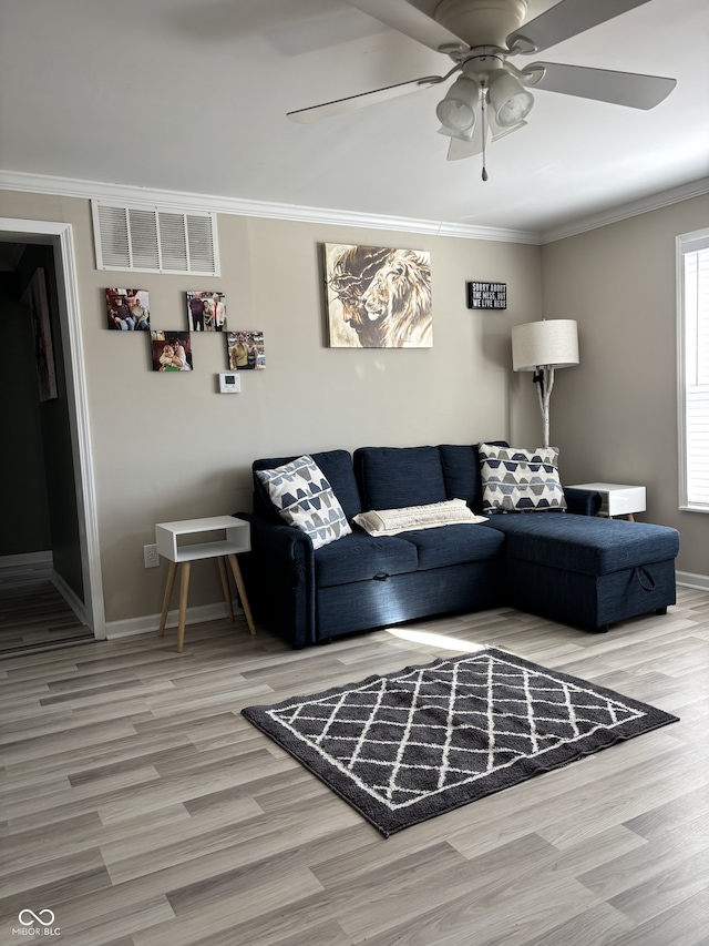 living area featuring ornamental molding, wood finished floors, visible vents, and baseboards