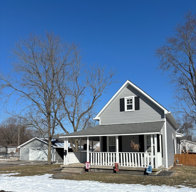 view of front of home featuring a porch, an outbuilding, roof with shingles, and a detached garage