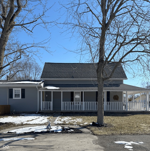 farmhouse inspired home featuring a carport, covered porch, and roof with shingles