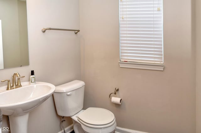 bathroom with baseboards, a sink, and toilet