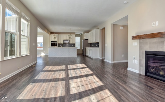 unfurnished living room featuring recessed lighting, baseboards, dark wood-style flooring, and a tile fireplace