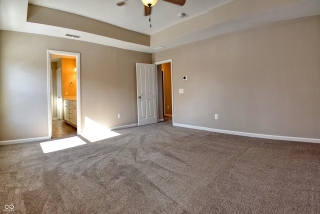 unfurnished bedroom featuring light carpet, baseboards, visible vents, and a raised ceiling