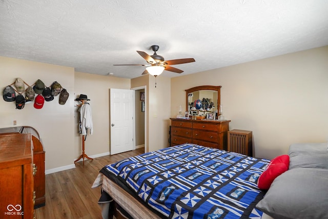 bedroom featuring a ceiling fan, a textured ceiling, baseboards, and wood finished floors