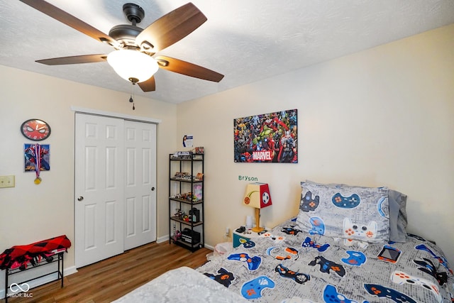 bedroom featuring a textured ceiling, ceiling fan, wood finished floors, baseboards, and a closet