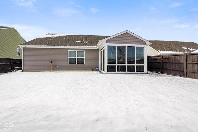 snow covered property featuring a sunroom and a fenced backyard