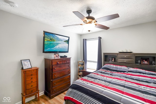 bedroom featuring a textured ceiling, ceiling fan, light wood finished floors, and baseboards