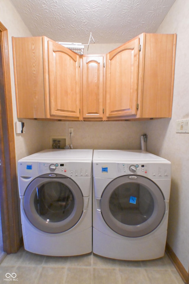 washroom featuring cabinet space, separate washer and dryer, a textured ceiling, and light tile patterned floors