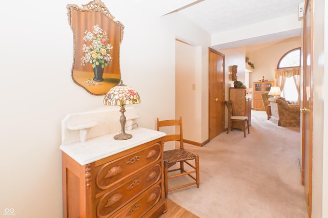 corridor featuring baseboards and light carpet