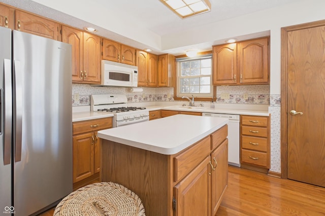 kitchen with white appliances, light countertops, a sink, and light wood-style floors