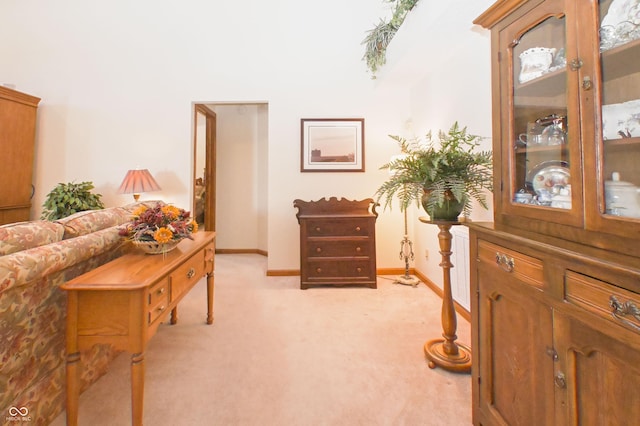 living area featuring baseboards and light colored carpet