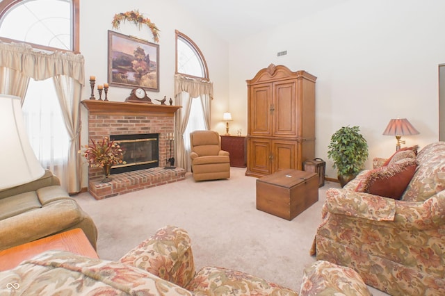living area featuring a high ceiling, carpet flooring, a brick fireplace, and visible vents