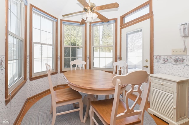 dining area with ceiling fan and wallpapered walls
