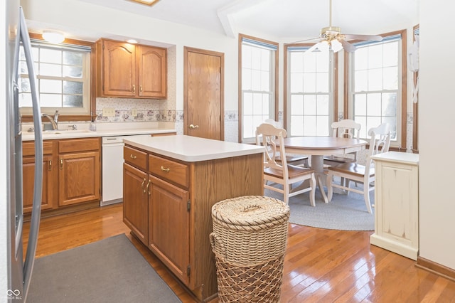 kitchen featuring a sink, light wood-style flooring, white dishwasher, and light countertops