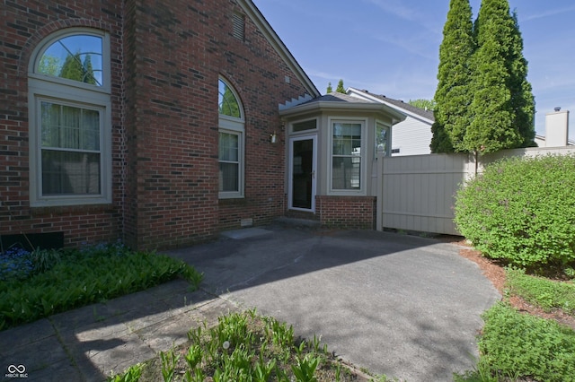 exterior space featuring fence, a patio, and brick siding