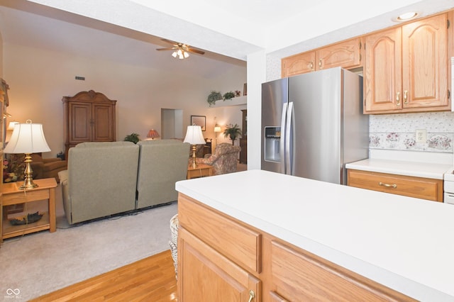 kitchen featuring ceiling fan, light countertops, stainless steel fridge with ice dispenser, open floor plan, and light brown cabinets