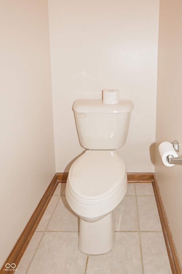 bathroom with toilet, baseboards, and tile patterned flooring