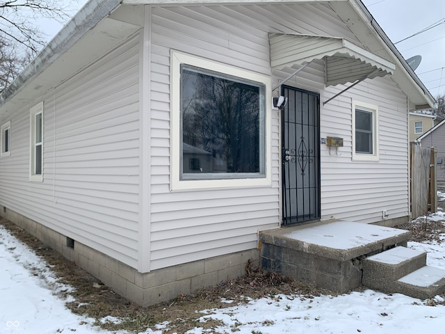 snow covered property entrance featuring crawl space