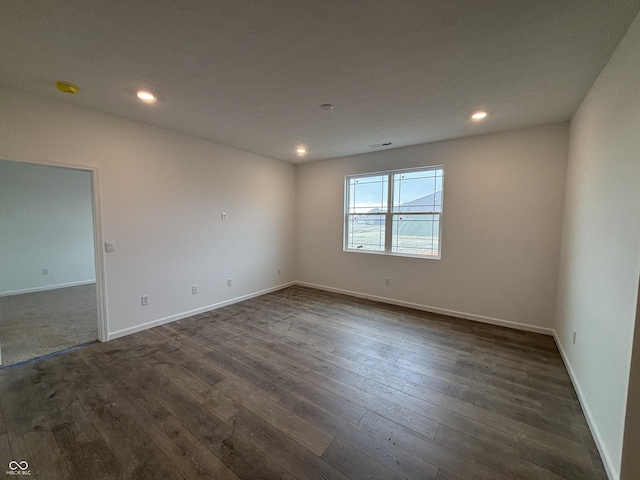 spare room featuring dark wood finished floors, visible vents, recessed lighting, and baseboards