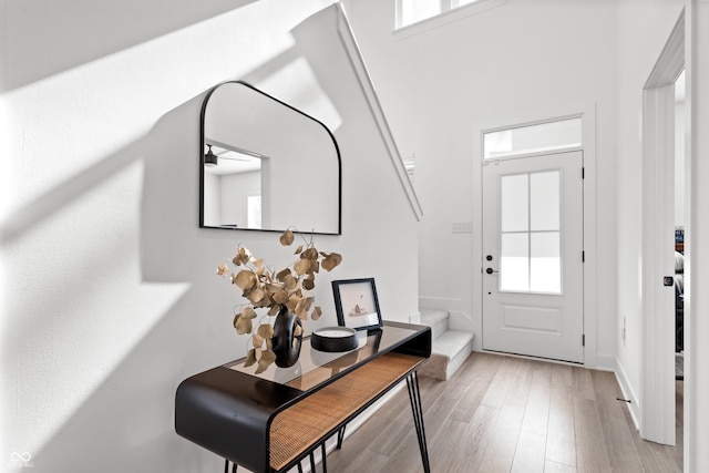 entrance foyer featuring light wood-style floors, stairway, and baseboards