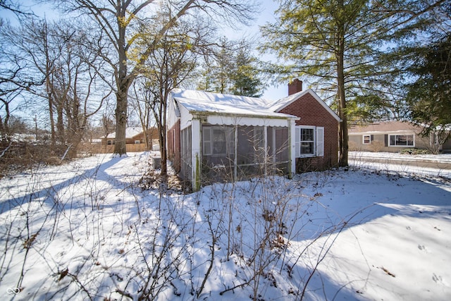 exterior space featuring a sunroom, brick siding, and a chimney