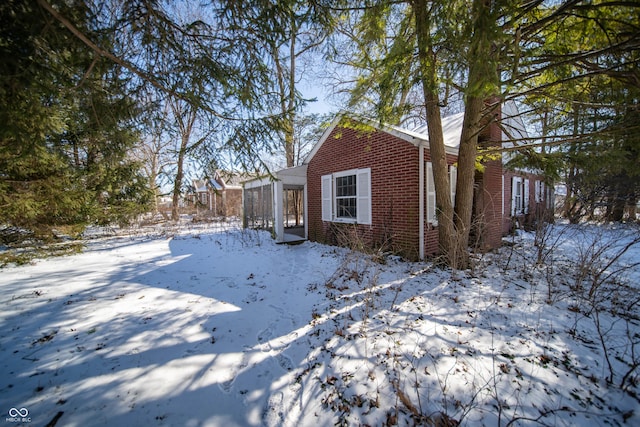 view of snow covered exterior featuring brick siding