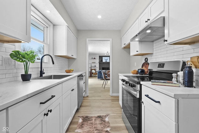 kitchen with under cabinet range hood, white cabinetry, stainless steel appliances, and light countertops