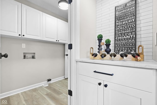 laundry area featuring baseboards, washer hookup, cabinet space, and light wood-style floors