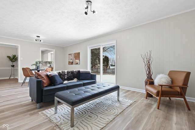 living area featuring baseboards, a textured ceiling, and light wood finished floors