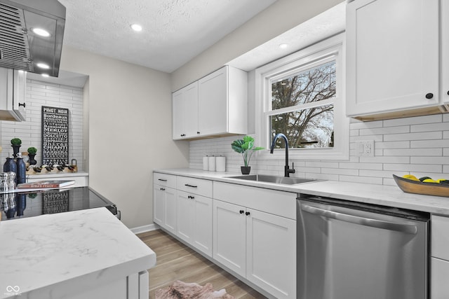 kitchen with white cabinets, dishwasher, light stone countertops, light wood-style floors, and a sink