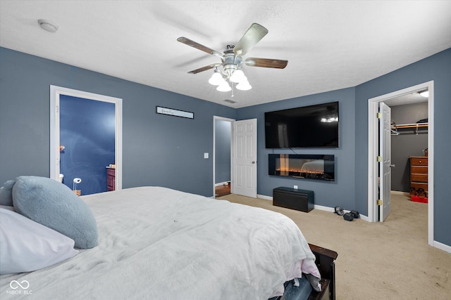 carpeted bedroom featuring ceiling fan, a closet, and a walk in closet