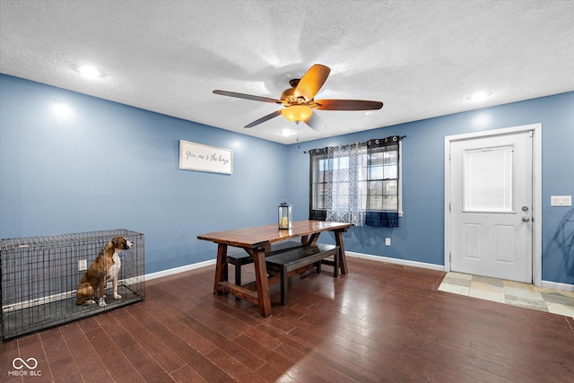 dining space featuring ceiling fan, dark wood-type flooring, and a textured ceiling