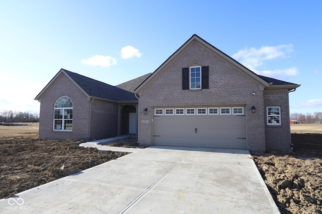 traditional-style house with a garage, concrete driveway, and brick siding