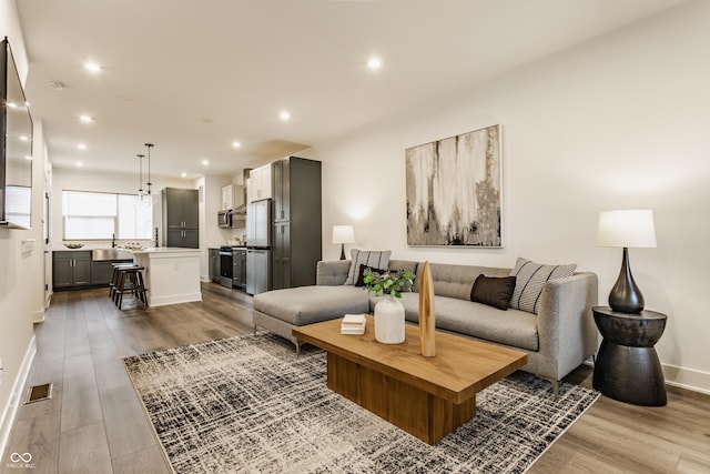 living room with baseboards, visible vents, wood finished floors, and recessed lighting