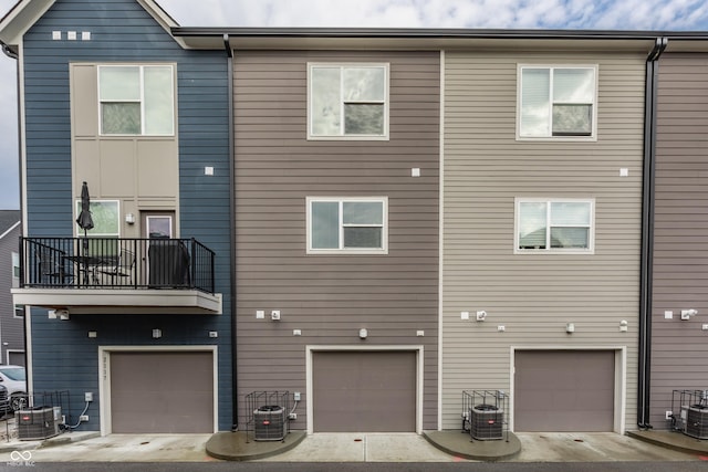 view of front of home featuring a balcony, an attached garage, and central AC unit