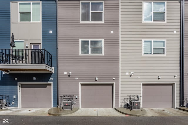 back of property featuring a garage, a balcony, and central AC unit