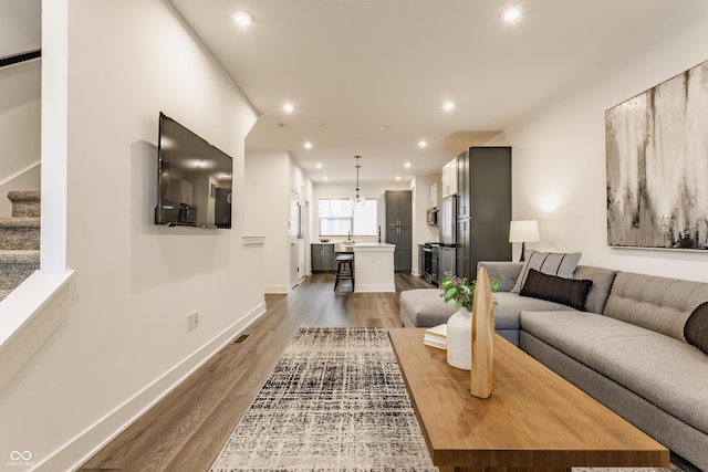 living room featuring dark wood-style floors, stairs, baseboards, and recessed lighting