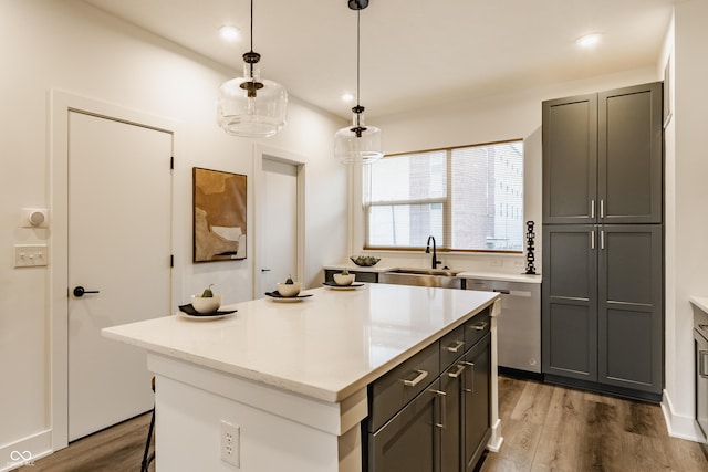 kitchen featuring hanging light fixtures, a kitchen island, a sink, and wood finished floors