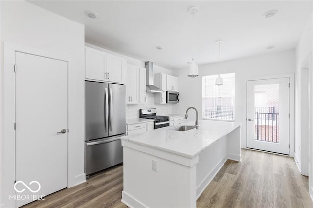 kitchen with a center island with sink, stainless steel appliances, hanging light fixtures, sink, and white cabinets